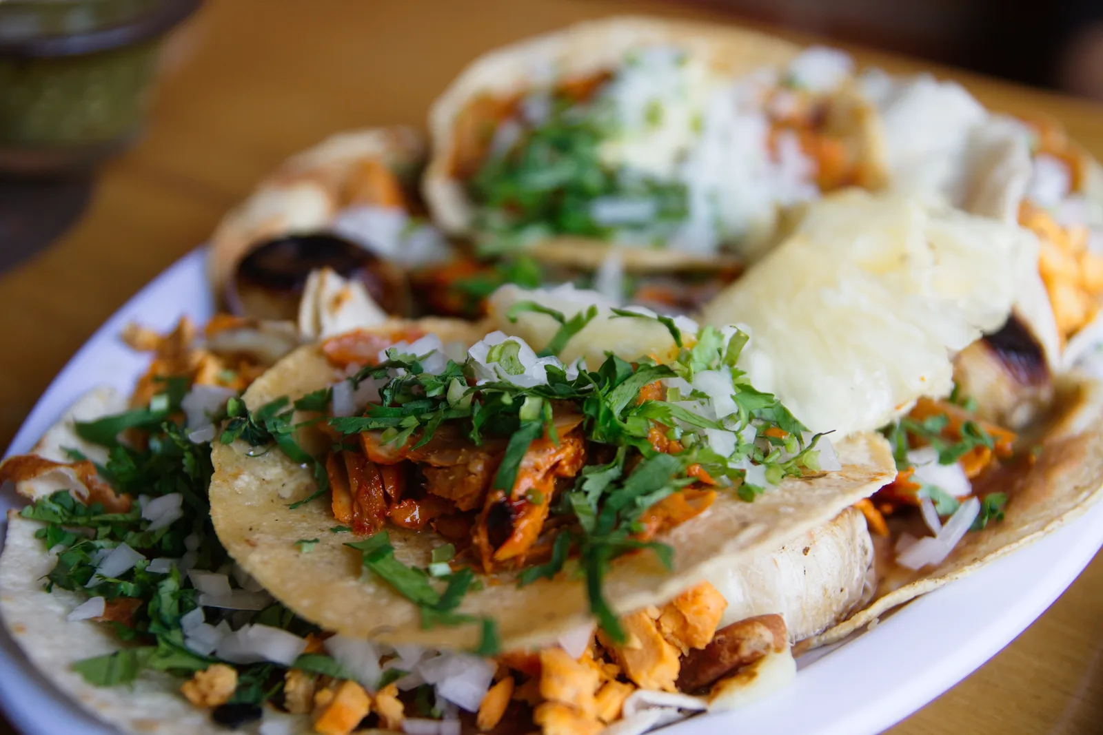 A plate of tacos al pastor topped with onion and cilantro. The photo was not taken at a Coral Gables restaurant.